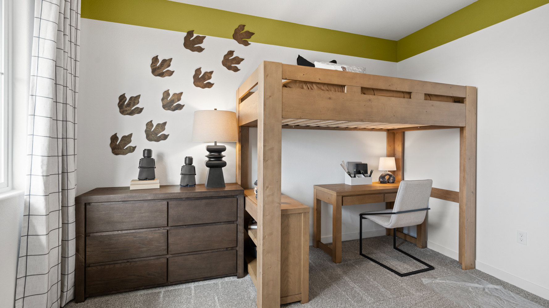 A room with a desk and a chair with a lamp and a wall with birds on it.