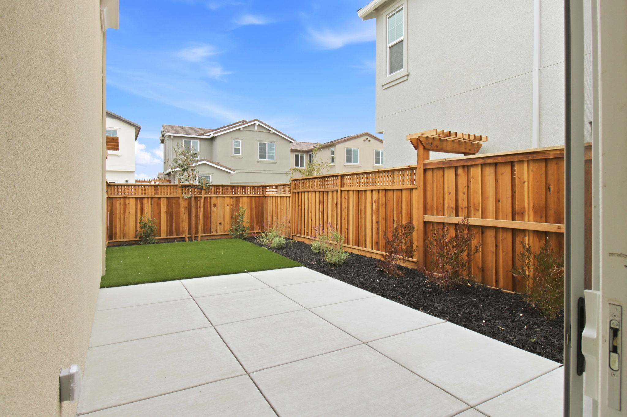 A backyard with a fence and a brick patio.