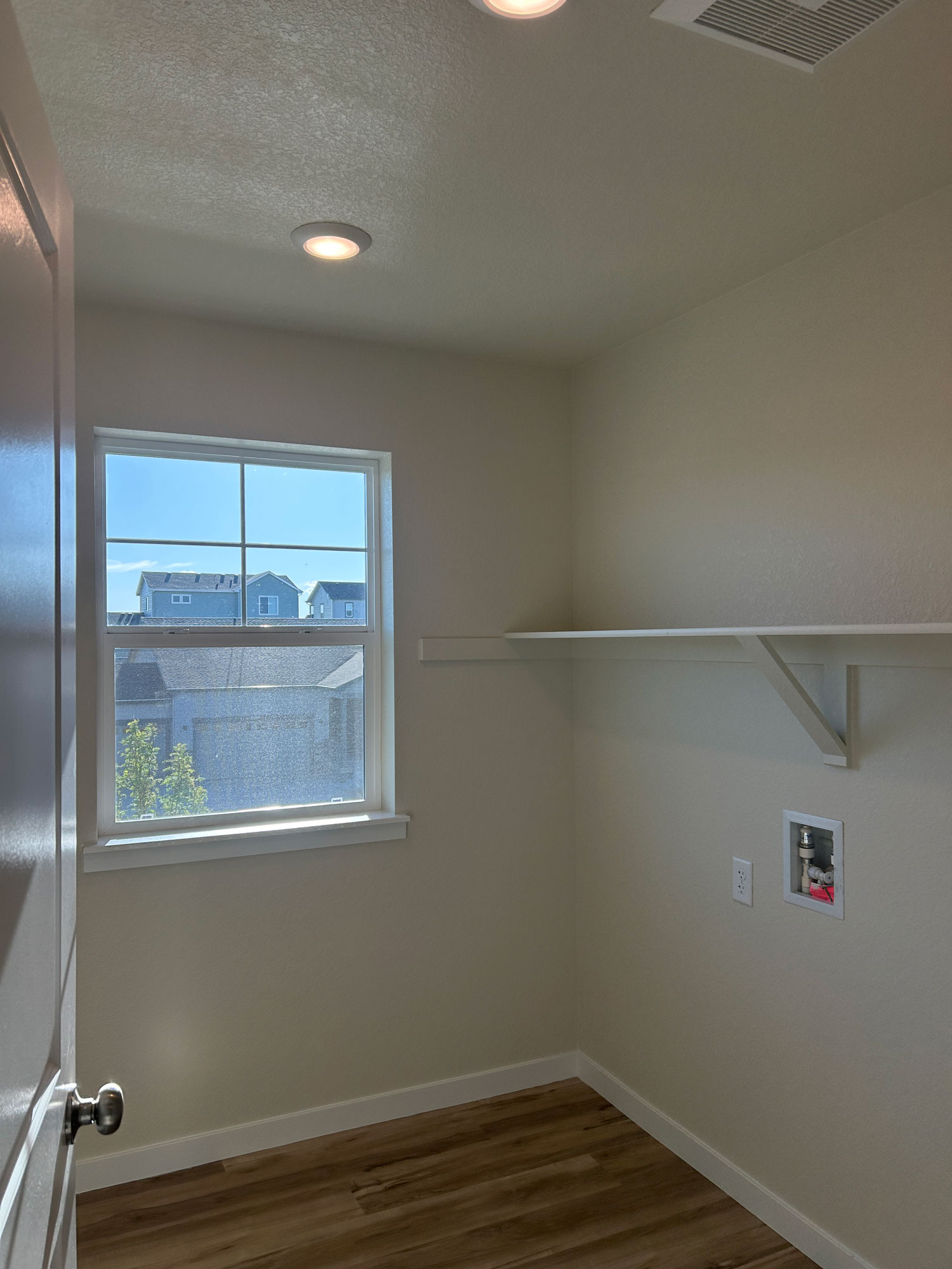 A room with a window and a wood floor.