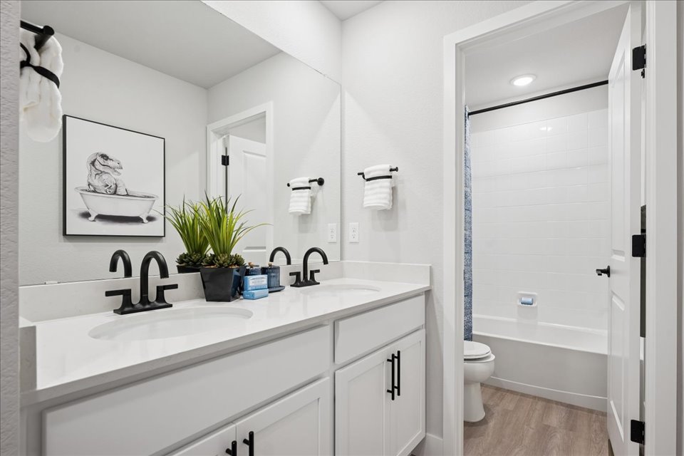 A bathroom with a sink toilet and mirror.