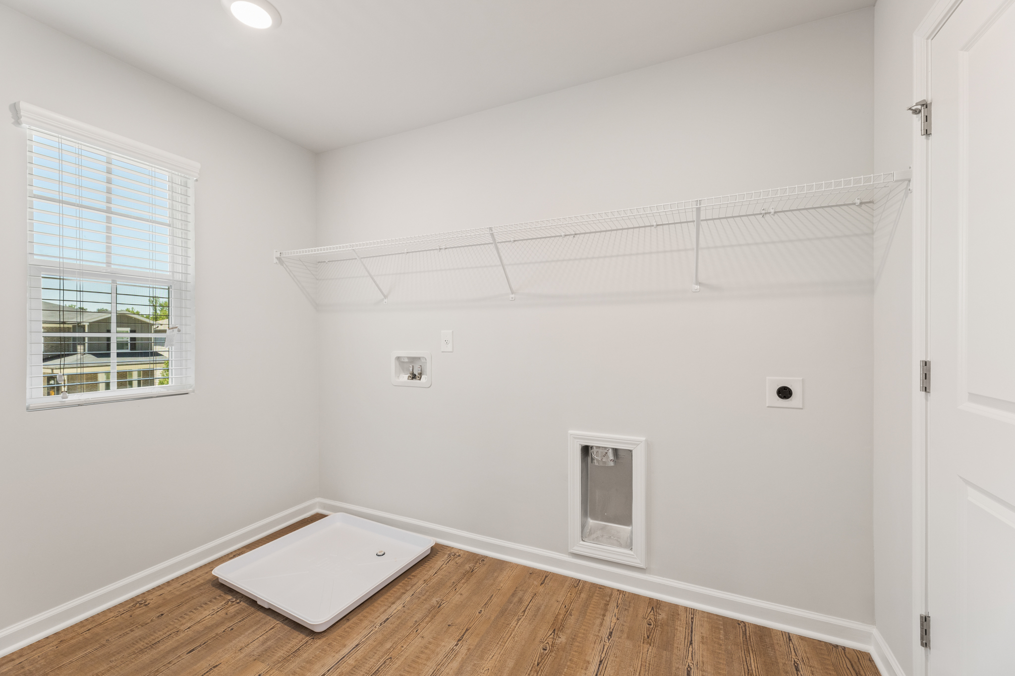 A room with a white wall and a wood floor.