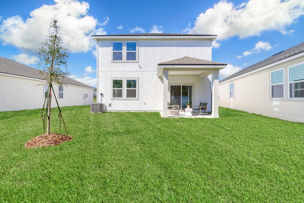 A house with a lawn and a tree in the front.