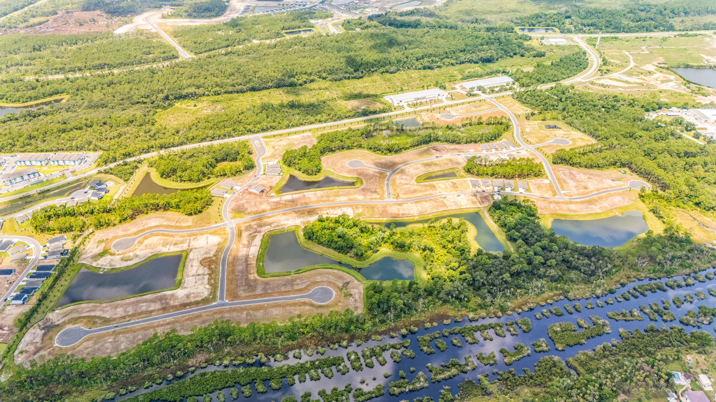 Reserve East by Century Communities in Flagler Beach Aerial View of Community with Paved Road, Ponds, and Quick Move-In Homes