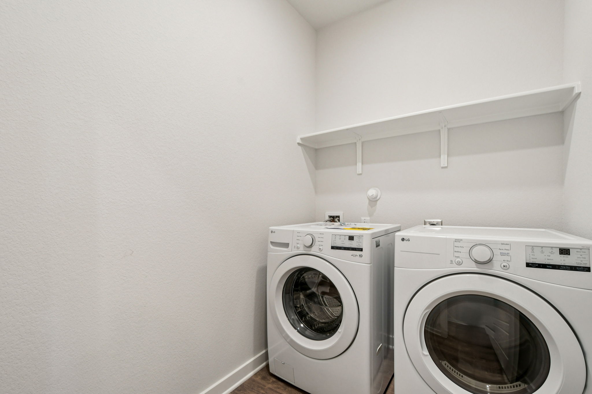 A white room with a washing machine and a dryer.