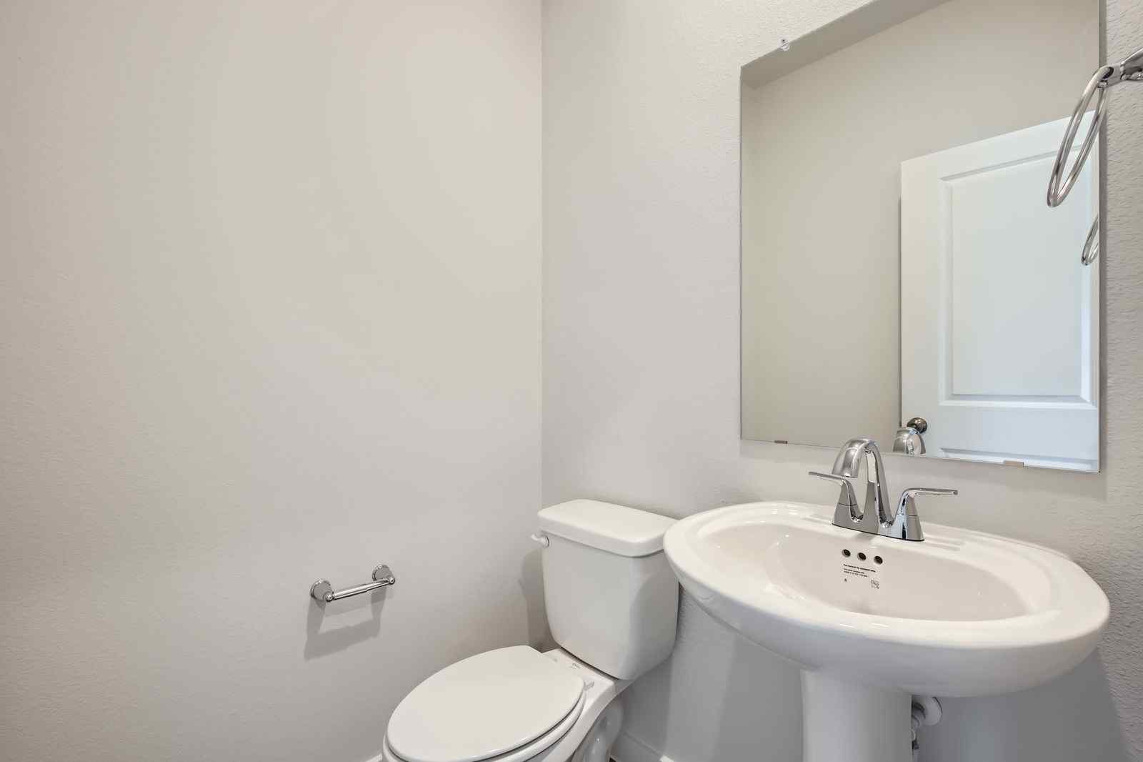 A bathroom with a sink toilet and mirror.