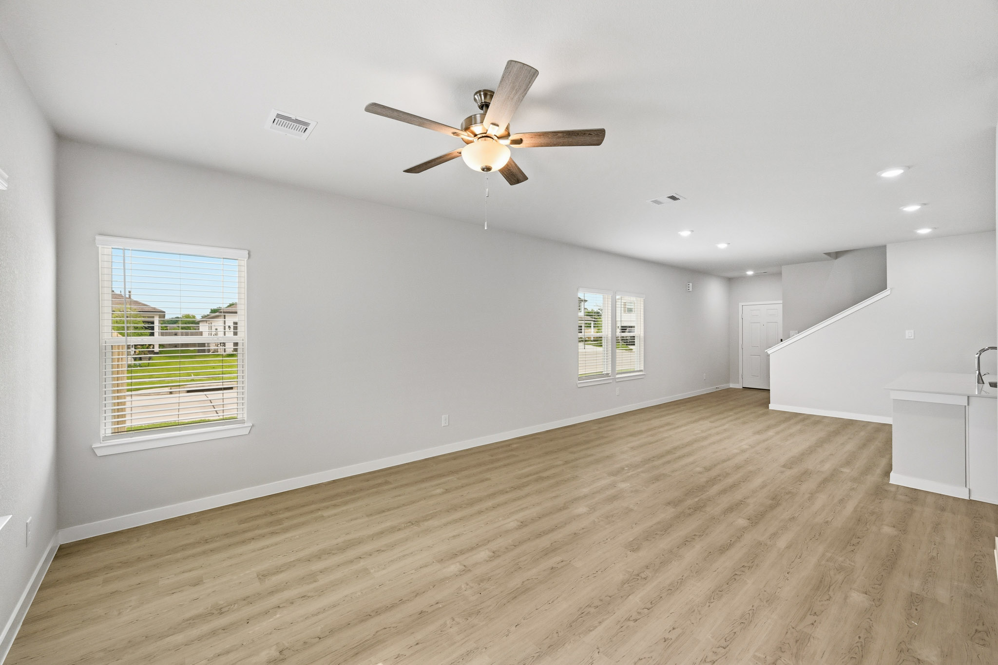 A room with a ceiling fan and a wood floor.