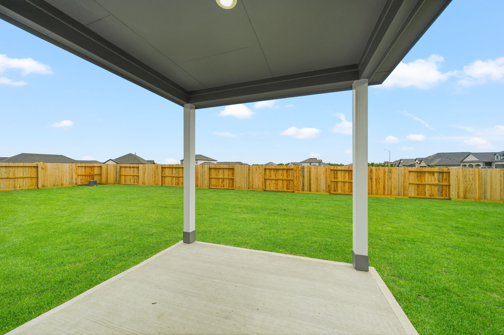 A walkway with grass and a fence.