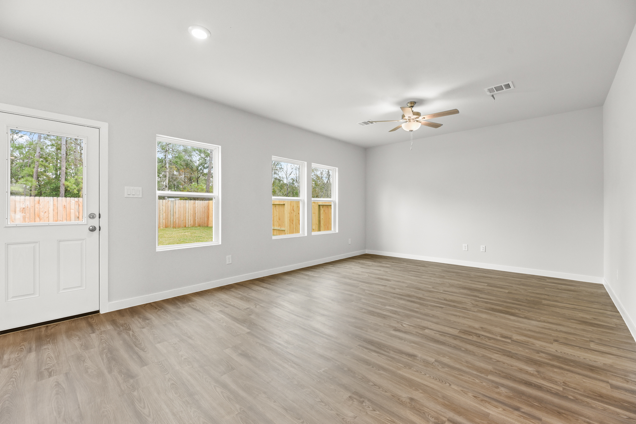 A room with a wood floor and a ceiling fan and a wood floor.