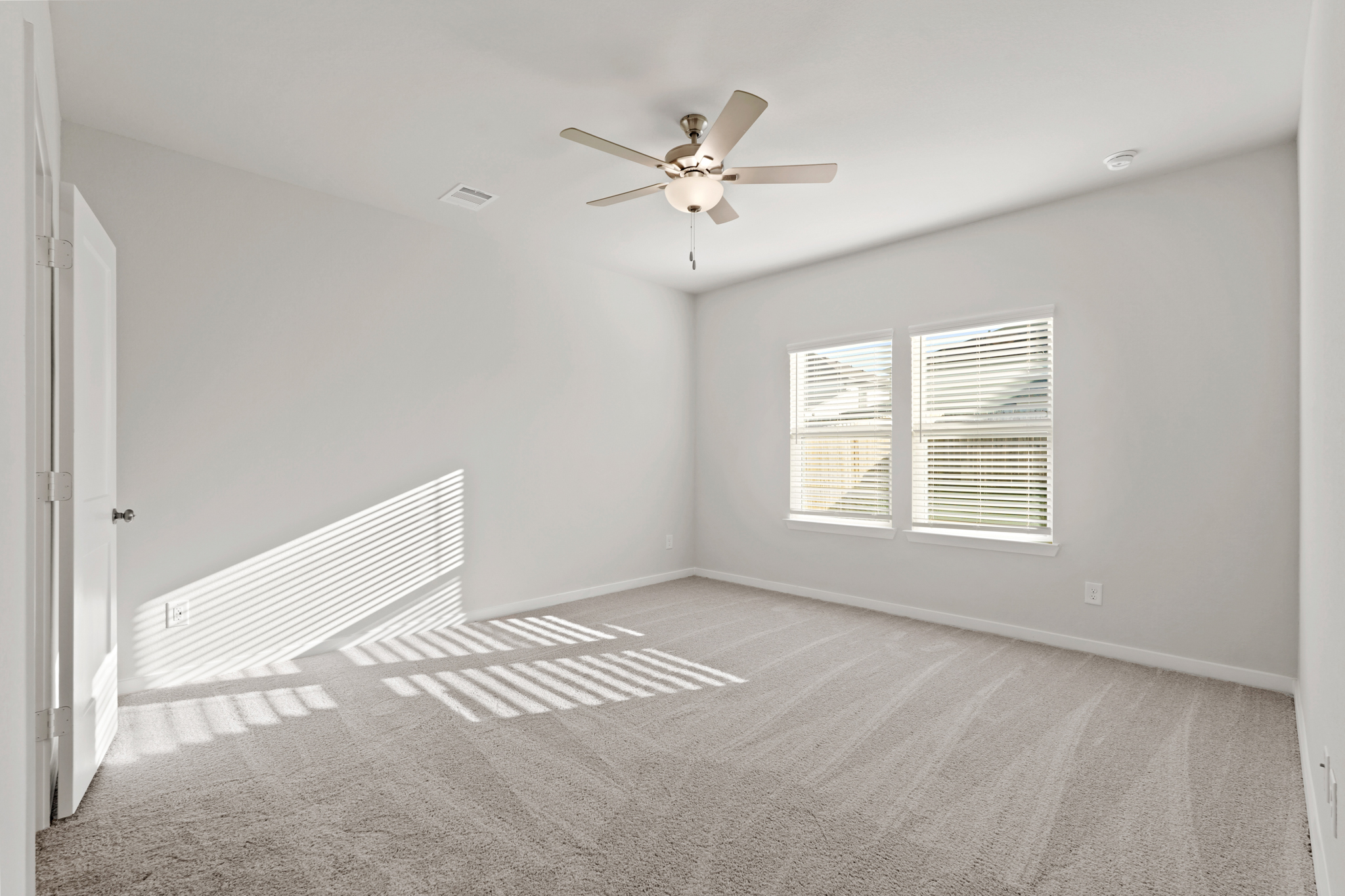 A room with a ceiling fan and a carpet.