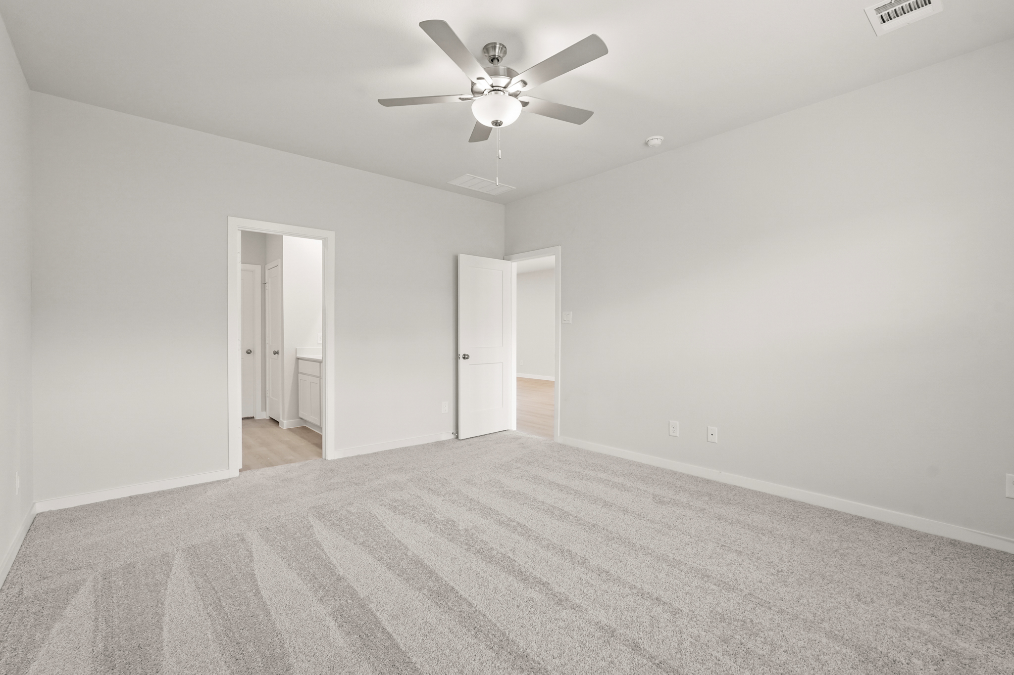 A room with a ceiling fan and a carpet.