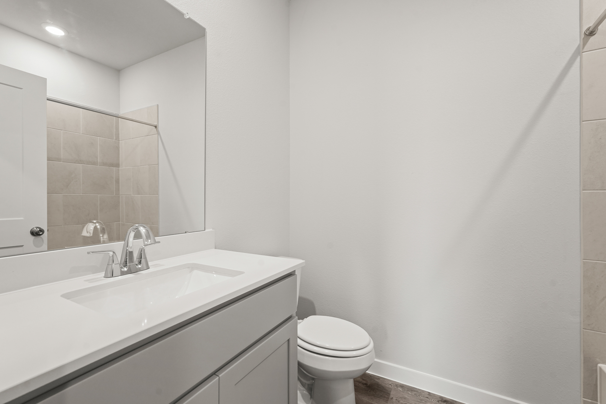 A bathroom with a sink toilet and mirror.