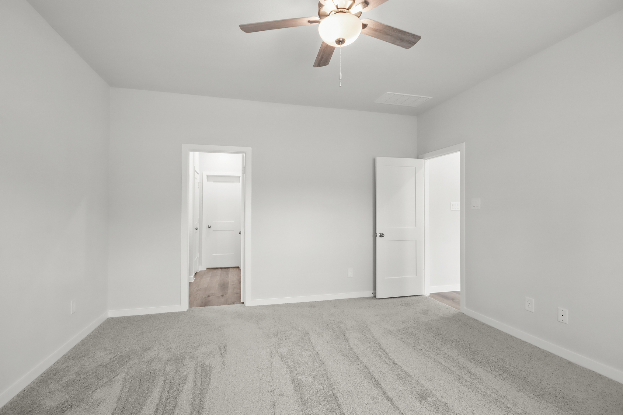A room with a ceiling fan and white doors.