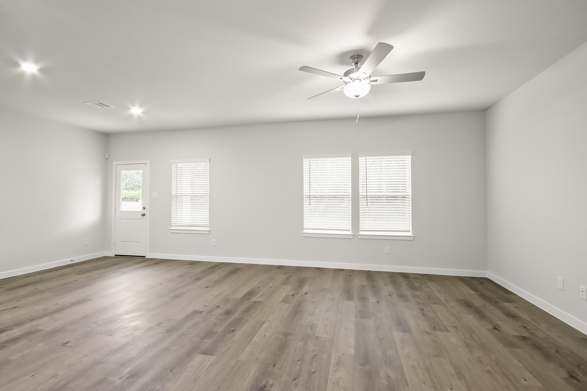 A room with a ceiling fan and a wood floor.