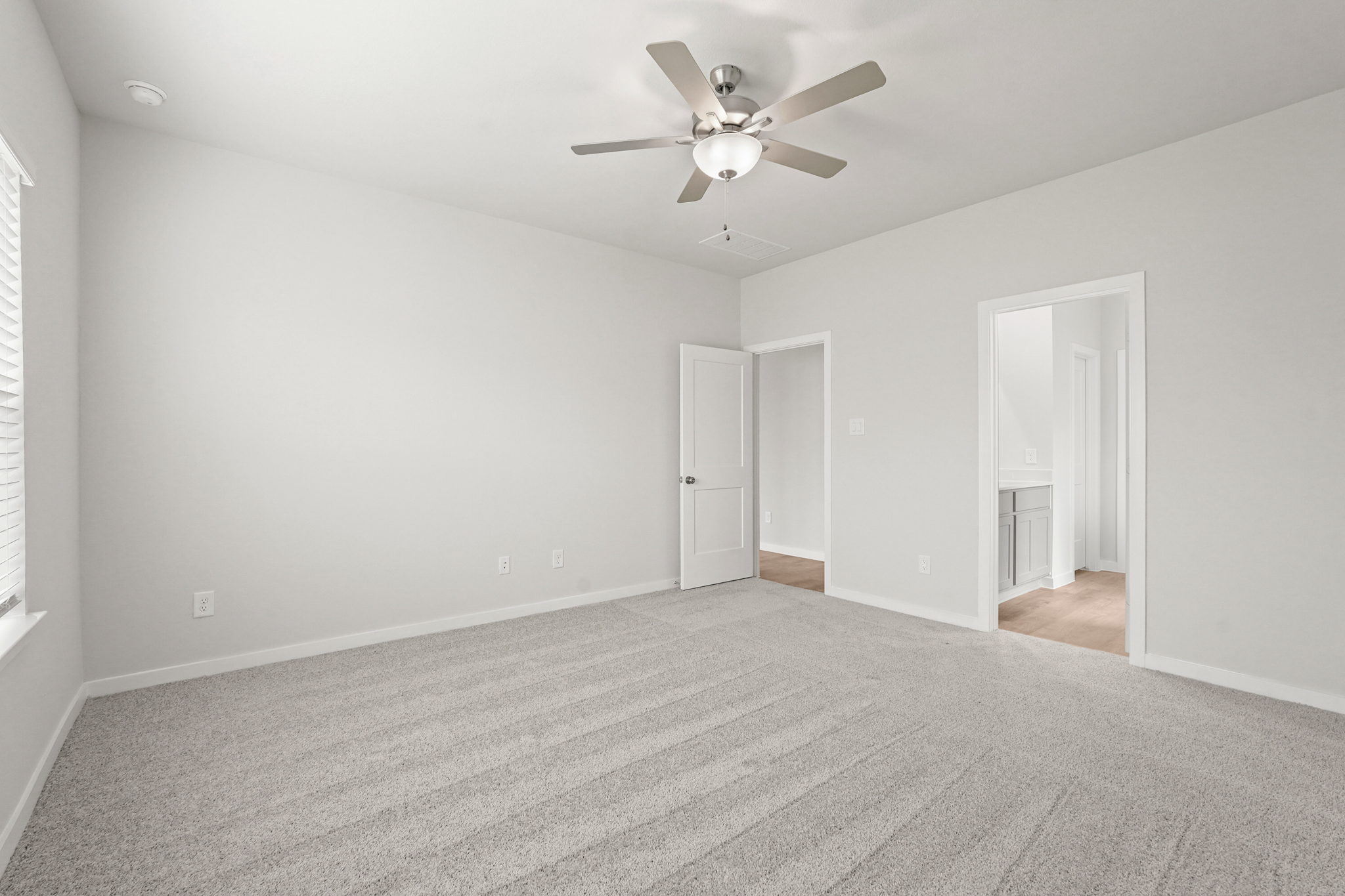 A room with a ceiling fan and a door.
