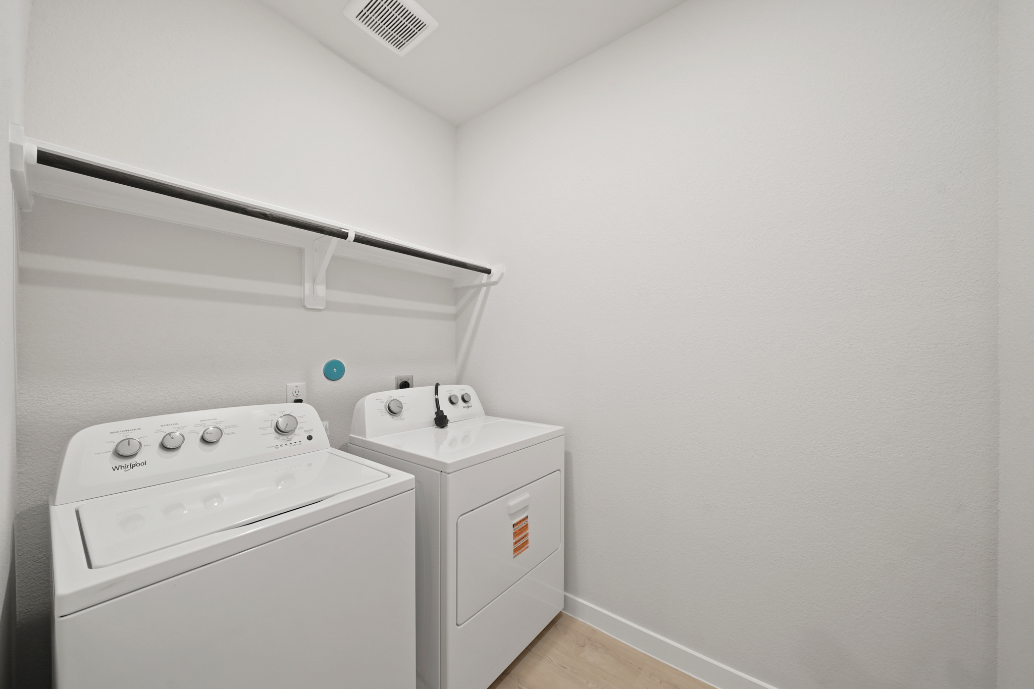 A white room with a washing machine and a dryer.