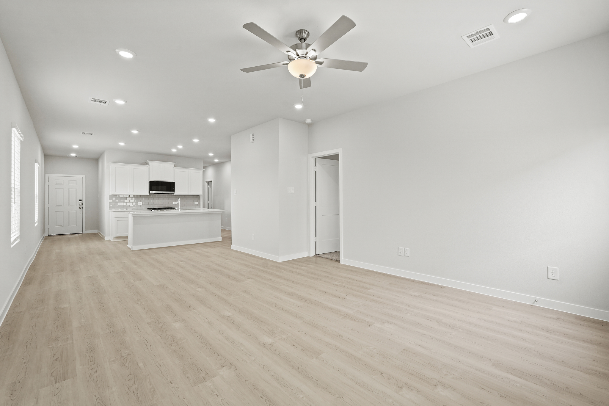 A large empty room with a ceiling fan and a wood floor.