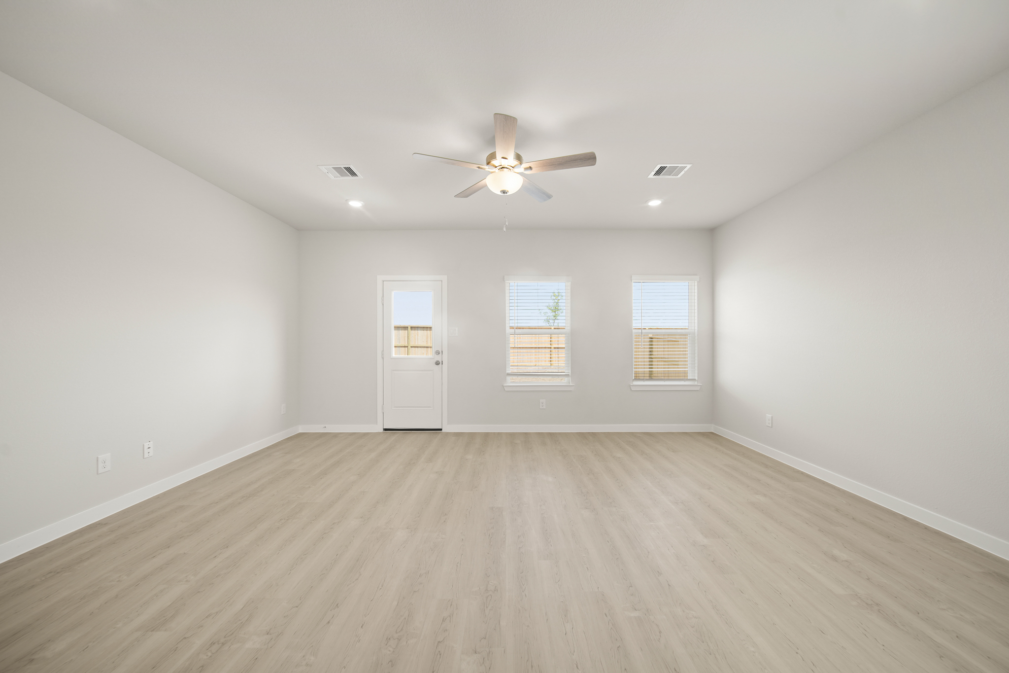 A room with a ceiling fan and a wood floor.