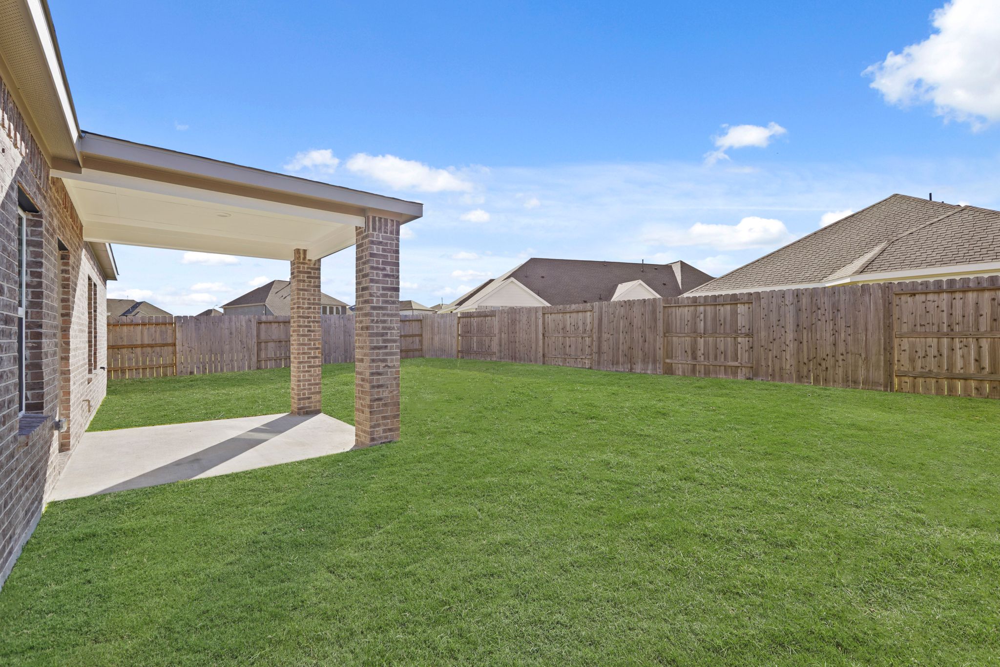 A fenced in yard with a brick building and a brick wall.