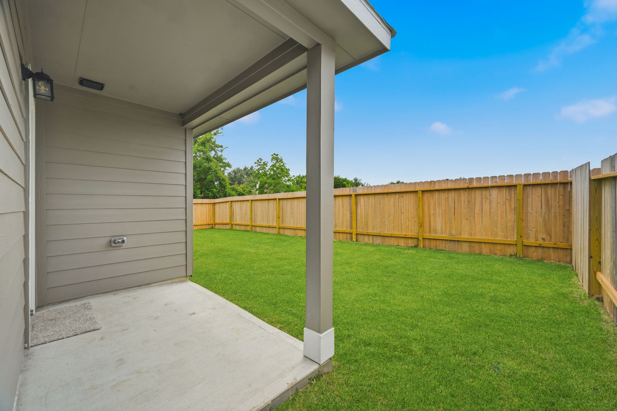 A backyard with a fence and a wood gate.
